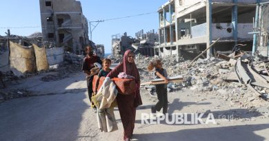 Warga Palestina, Amal Alyan bersama keluarganya berjalan di lingkungan rumah mereka yang hancur akibat serangan Israel, di Kota Gaza, Ahad (26/10/2025).