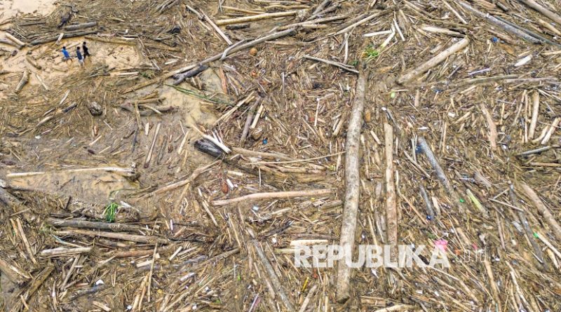 Foto udara sejumlah warga berjalan di antara potongan kayu gelondongan yang bertumpuk di pantai Air Tawar, Padang, Sumatera Barat, Jumat (28/11/2025). Sampah kayu gelondongan itu menumpuk di sepanjang pantai Padang pasca banjir bandang beberapa hari terakhir.