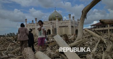 Warga beraktivitas diantara tumpukan kayu yang memenuhi area Pesantren Darul Mukhlisin dan pemukiman di Desa Menanggini, Aceh Tamiang, Aceh, Jumat (19/12/2025).