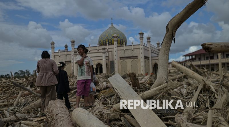 Warga beraktivitas diantara tumpukan kayu yang memenuhi area Pesantren Darul Mukhlisin dan pemukiman di Desa Menanggini, Aceh Tamiang, Aceh, Jumat (19/12/2025).