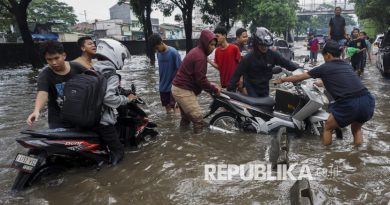 Residents help a stalled motorcyclist navigate floodwaters on Jalan Daan Mogot, Jakarta, Thursday (January 22, 2026). Floodwaters 50-60 cm deep due to heavy rain and poor drainage caused several vehicles to stall and disrupt traffic.